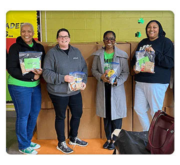 Square shaped photo of four women holding community donation items
